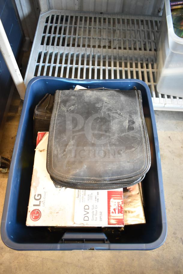 Lot of 2 bins with LG DVD player, DVDs, and a black case. Items are in used condition, visible dust on case.