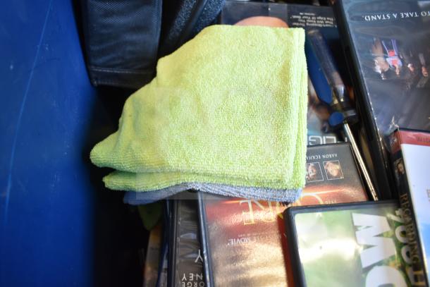 Lot of various items in a blue bin, including DVDs, a green cloth, and a screwdriver. LG DVD player not visible.