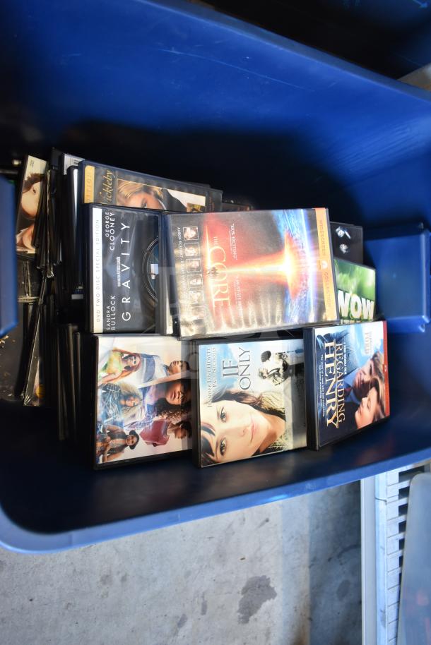 Lot of DVDs in a blue bin, including titles like "Gravity" and "The Core". Part of a 2-bin auction lot with an LG DVD player.