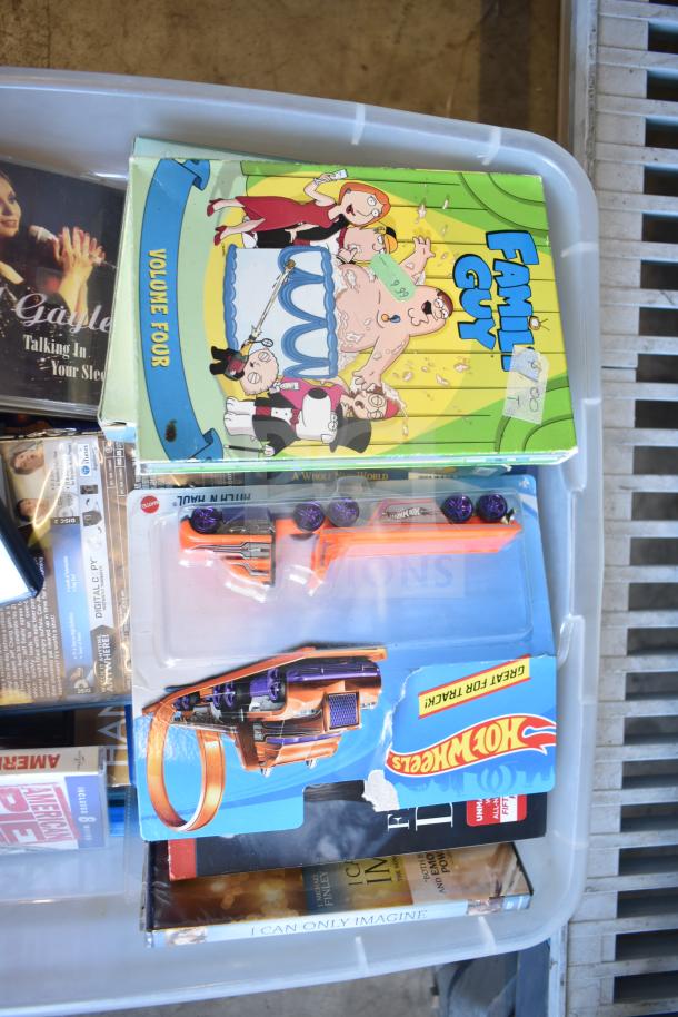 Lot including "Family Guy" Volume 4 DVD, Hot Wheels toy car sealed, assorted DVDs in plastic bin.