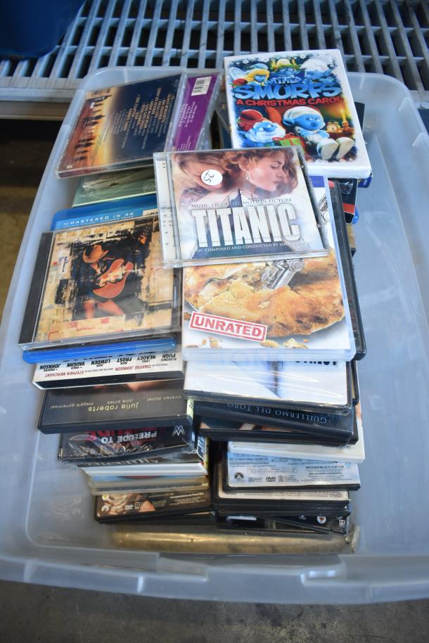Lot of 2 bins with various items including DVDs and a mix of media. Condition: mixed. Some cases marked with titles.