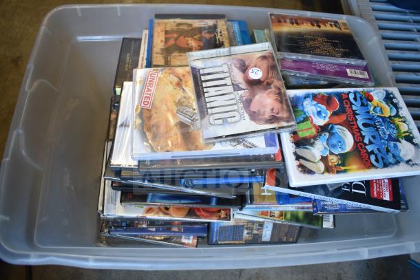 Lot of DVDs in plastic bin, includes "Titanic" and "The Smurfs Christmas Carol," assorted titles, visible price tags.