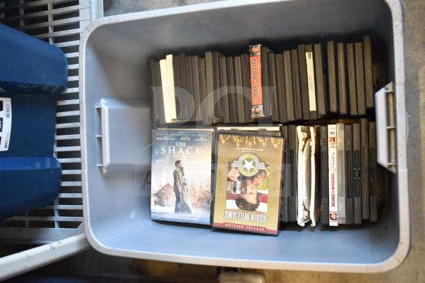 Lot of DVDs in a bin, including "The Shack," "Robin Williams," and others. Mixed titles, condition varies.