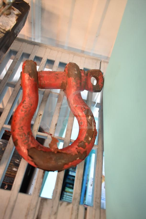 Red metal hitch with visible rust and paint chipping, marked "USA." Part of a lot including knife, screwdriver, and tape.