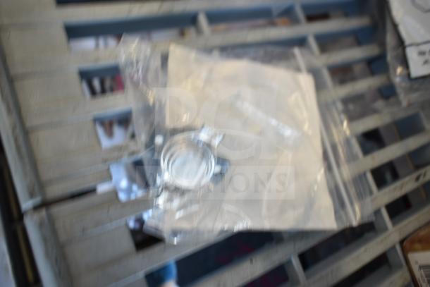 Blurred image of a sealed plastic bag with assorted items, part of a lot including a USA Wolf Streak knife and cordless screwdriver.