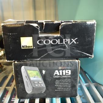 Nikon CoolPix digital camera box and SpyTec A119 dash camera box showing visible wear, on metal shelf.