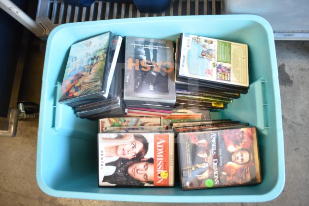 Lot of various DVDs in a large blue poly bin, featuring multiple genres and titles, some marked as rentals.