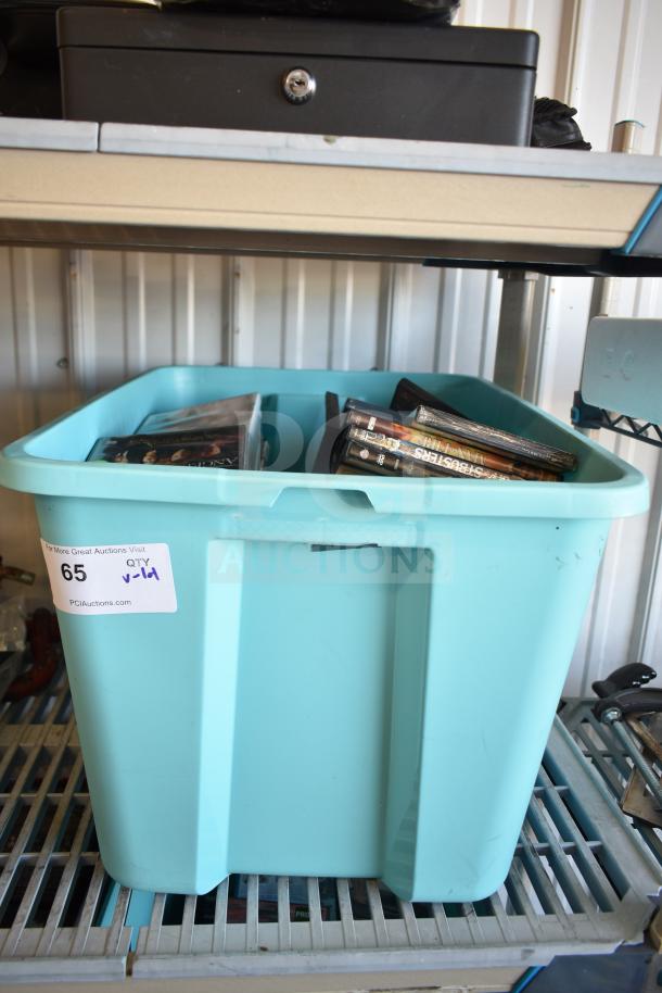 Lot of various DVDs in a blue poly bin, some visible titles. Bin labeled with auction info, item no. 65.