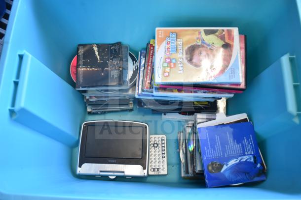 Lot of various DVDs in a blue poly bin, includes a portable Coby DVD player. Mixed titles, visible wear on cases.