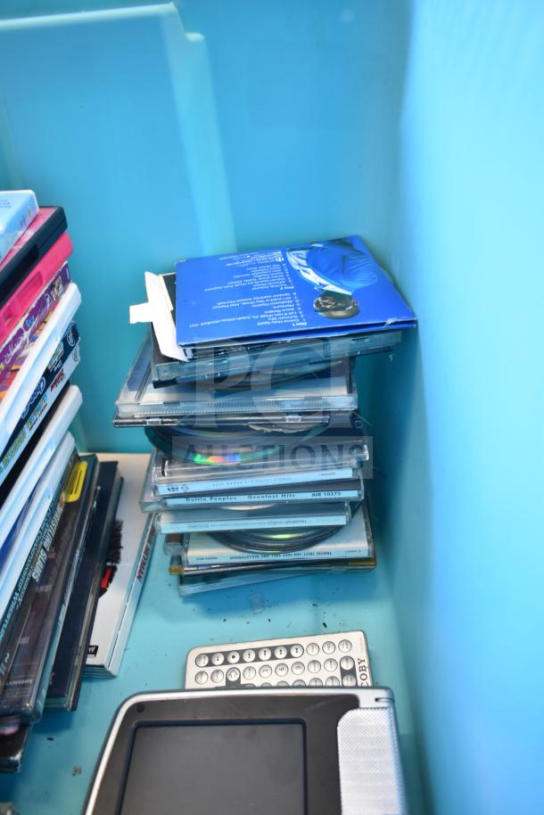 Lot of various DVDs in a blue poly bin, stacked in cases. Mixed genres, good condition. Ideal for collectors.