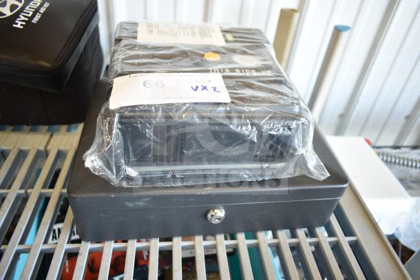 SentrySafe cash box, new, with locking mechanism, atop flat tire repair kit in plastic wrap. Auction label "66 VXZ" visible.