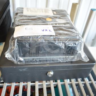 SentrySafe cash box, new, with locking mechanism, atop flat tire repair kit in plastic wrap. Auction label "66 VXZ" visible.