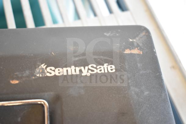 SentrySafe cash box with visible wear and scratches. Brand logo on lid. Auction includes flat tire temporary repair kit.