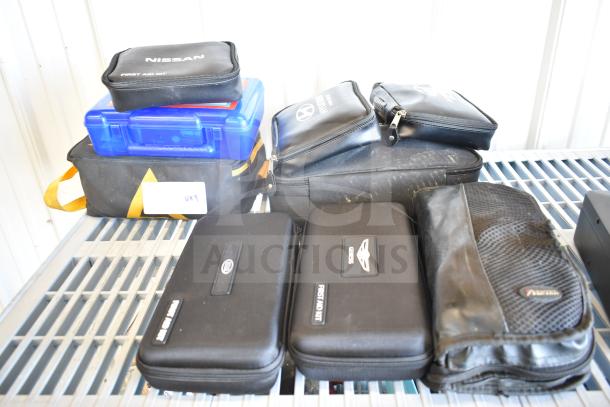 Assorted first aid and roadside kits from Hyundai, Nissan, Genesis, Kia, and Volkswagen on a shelf; varying conditions.