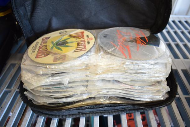 A collection of CDs encased in protective sleeves within a zippered black case, featuring titles like "Bob Marley."