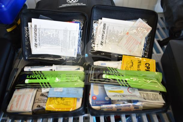 Nine assorted first aid and roadside kits, including Hyundai, Nissan, Genesis, Kia, and a VW kit with comprehensive supplies.