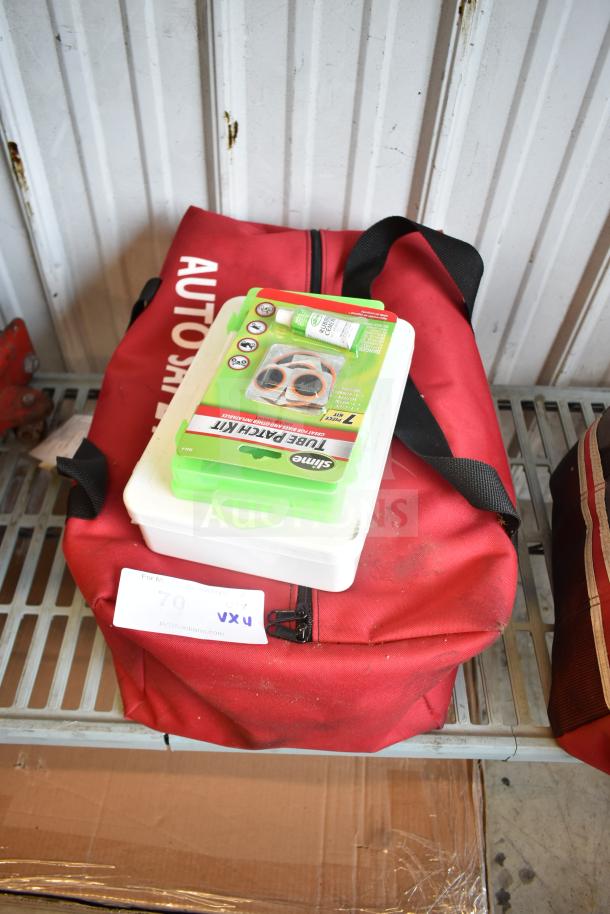 Red auto safety bag with a Slime Tube Patch Kit and white Cintas first aid kit on top, against a metal wall. Signs of wear.