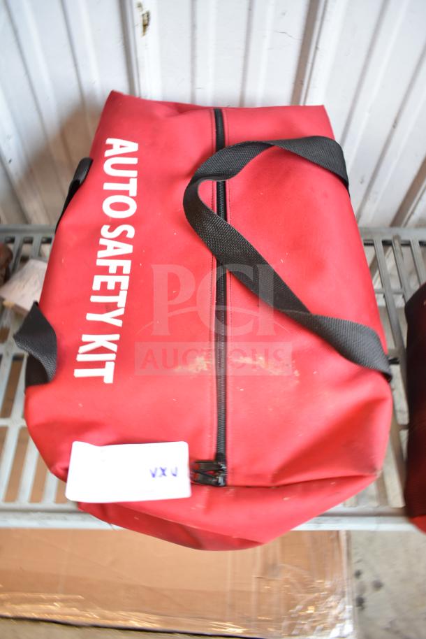 Red auto safety kit bag with black strap, visible dirt, and label. Part of auction lot with Slime Tube Patch Kit, Tire Tackle, and Cintas First Aid Kit.