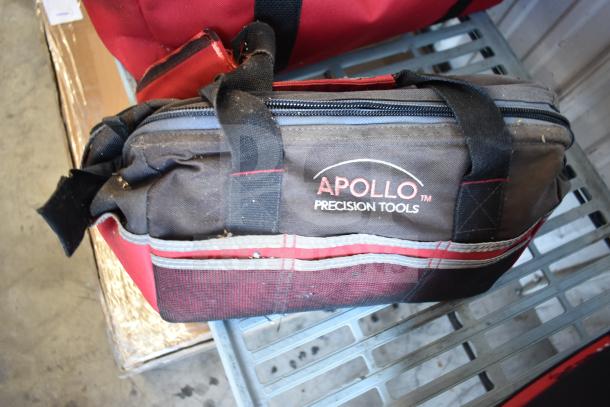 Red and black Apollo Precision Tools bag on a shelf, containing various items including jumper cables, in used condition.
