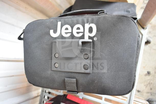 Jeep-branded black bag containing jumper cables and other items, in good condition, sturdy handle.