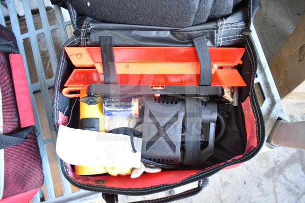 Bag containing emergency tools, including jumper cables, reflective triangle, portable air compressor, and flashlight.