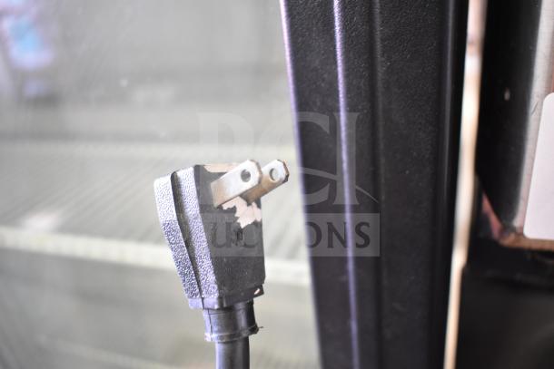 True GDM-26 commercial cooler plug detail, 115V, 1-phase. Power cord and metal door frame visible, light wear shown.