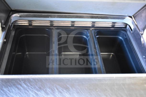 Delfield UCD4464N-12-DD5 sandwich prep table interior view showing empty black pans, stainless steel construction, clean condition.