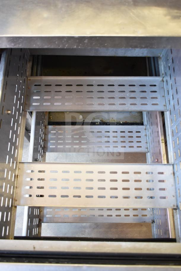 True TPP-93D-6 commercial pizza prep table interior with six perforated metal drawers on commercial casters, 115 volts.