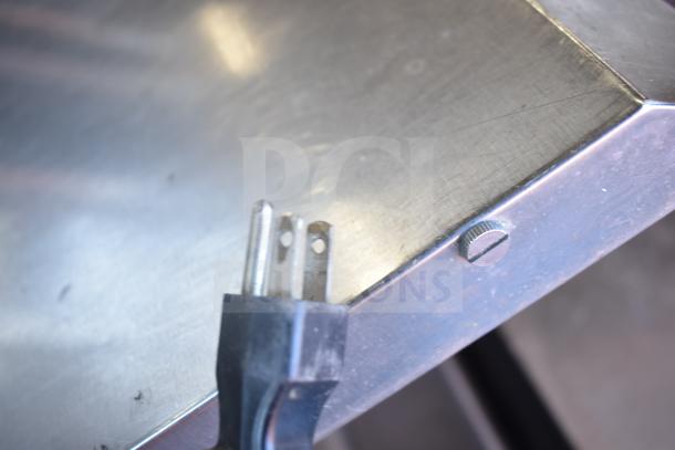 Commercial iced tea machine plug and metal surface detail, showcasing a 120V power connection for countertop use.