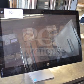 HP All In One Computer with black bezel and silver stand, reflective screen, auction tag 92 visible, in used condition.