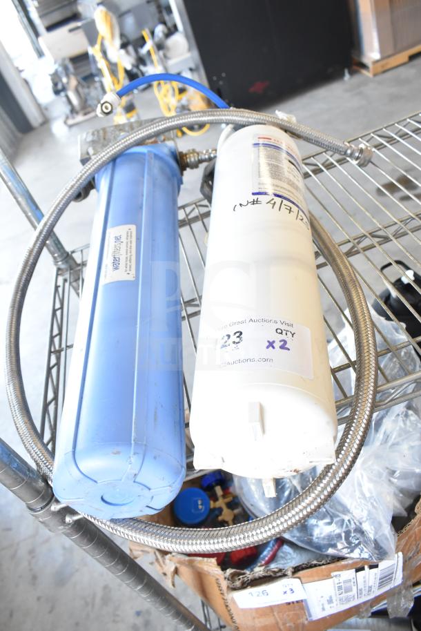 Water filtration system with blue and white filters, metal hose, and labels indicating auction details. Good condition.
