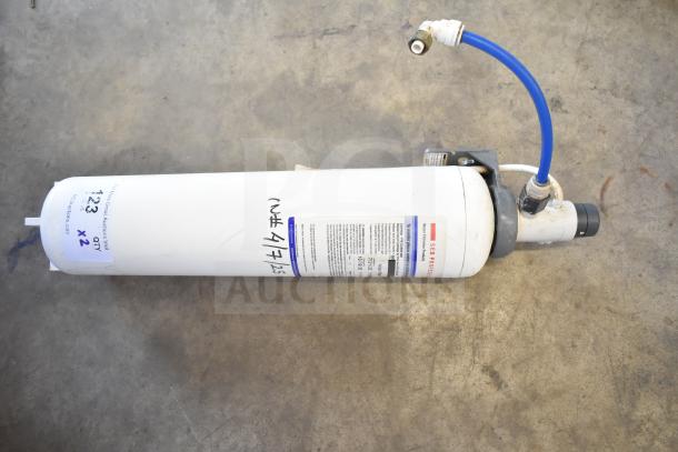 Water filtration system, white cylindrical unit with blue hose, model SEB Protect. Features performance labels, used condition.