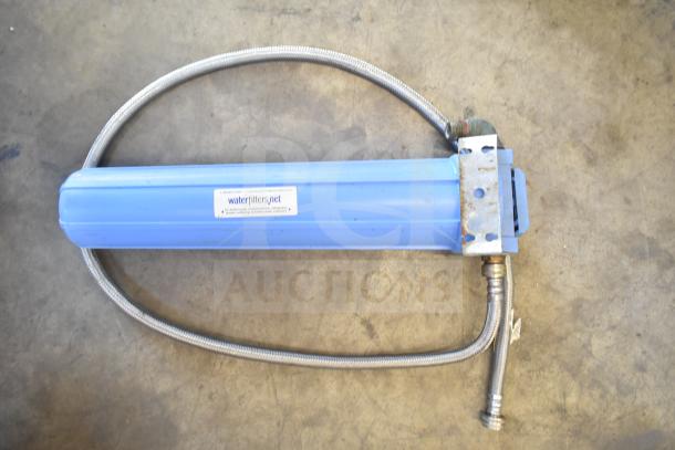 Blue water filtration system with attached hoses. Features a "waterfilters.net" label. Some rust visible on metal bracket.