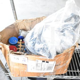 Lot of various items including gauges, hoses, metal pieces in a worn cardboard box, with shipping labels visible.