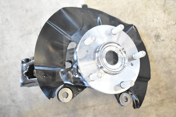 Various automotive parts including a wheel hub assembly with black backing plate and metallic finish, in good condition.