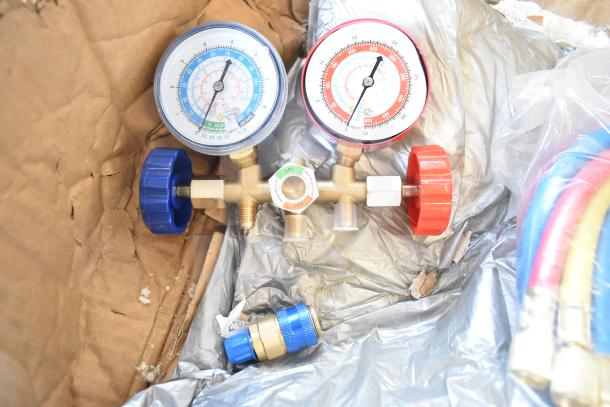 Lot featuring dual pressure gauges with red and blue dials, hoses, and brass connectors, in used condition.