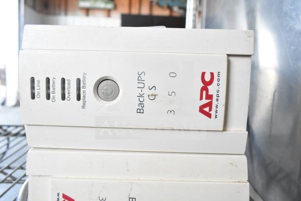 Two APC Back-UPS CS 350 units, white casing, indicated settings for On Line, On Battery, Overload, Replace Battery.