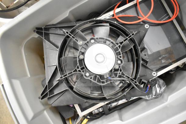 Gray bin containing various items including a Kitchen Armor monitor, Netgear router, and PlayStation controllers with cables.