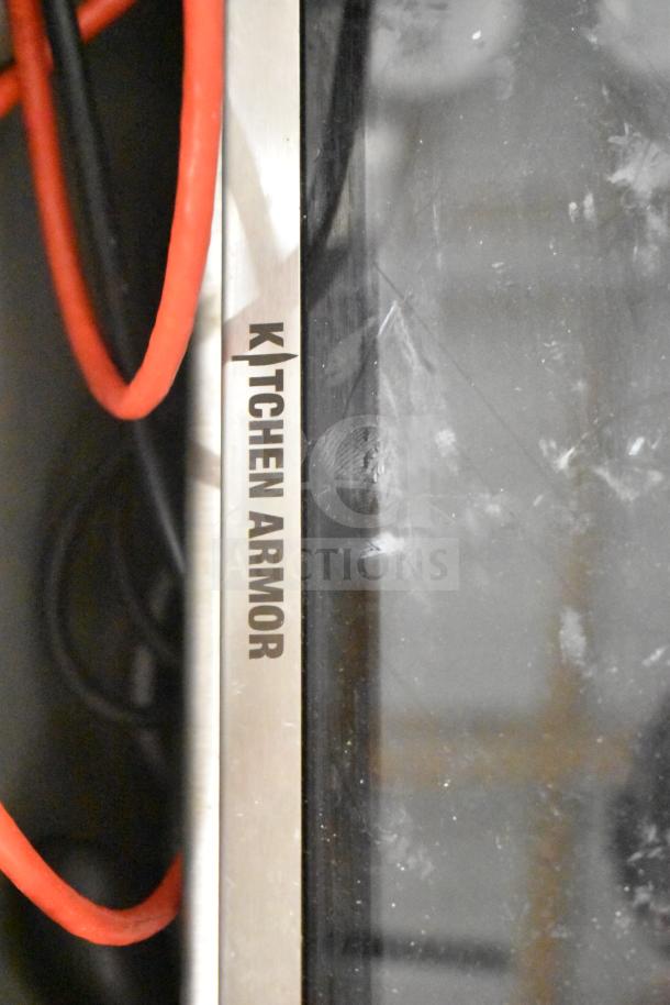 Lot of items including a Kitchen Armor monitor, visible with a metallic edge and cables, in a gray bin.