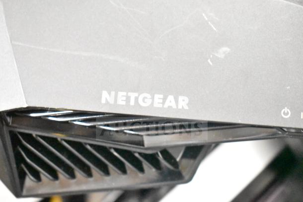 Netgear router in used condition, part of auction lot with various items including PlayStation controllers and cables.