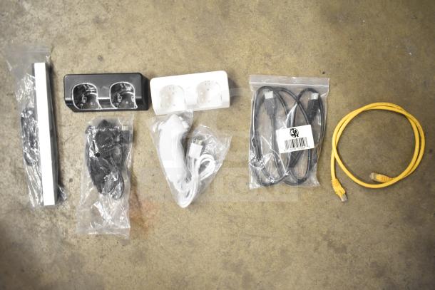 Lot of items in gray bin including Kitchen Armor monitor, Netgear router, PlayStation controllers, and cables.