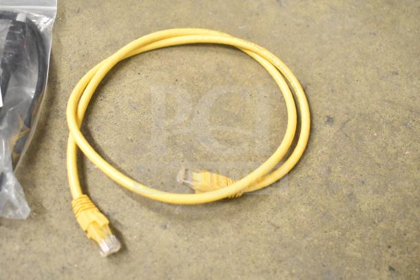Yellow Ethernet cable on the floor, part of a mixed auction lot with various electronics in a gray bin.