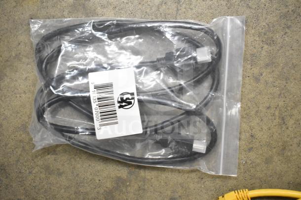 Gray bin containing various items including Kitchen Armor monitor, Netgear router, PlayStation controllers, cables. Plastic bag holds a black cable with a white connector and barcode tag.