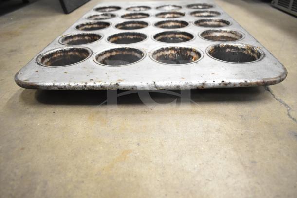 Metal muffin baking pan with 24 cups, showing signs of wear and rust. Part of a lot including mesh baking pans.