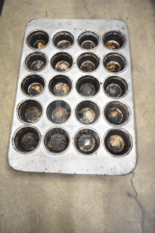 Used muffin baking pan with 24 cups, showing signs of wear and residue. Ideal for bulk baking projects.