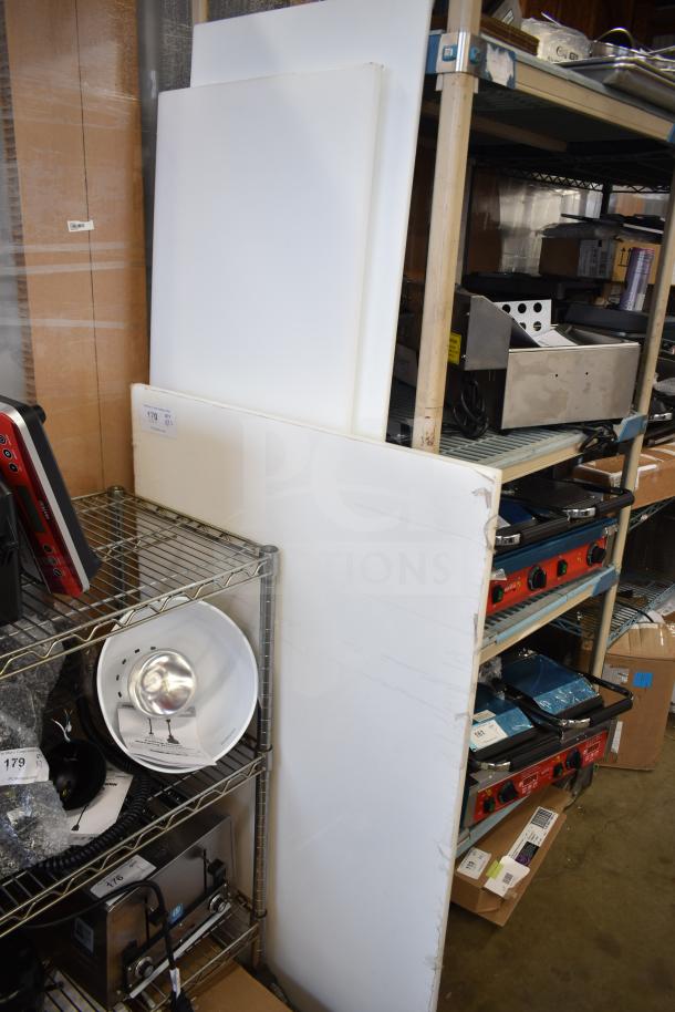 Three brand new scratch and dent cutting boards, large size, slightly damaged edges, white, displayed in storage area.