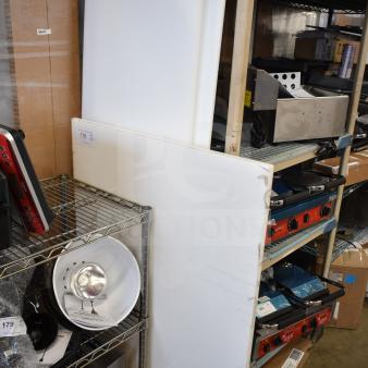 Three brand new scratch and dent cutting boards, large size, slightly damaged edges, white, displayed in storage area.