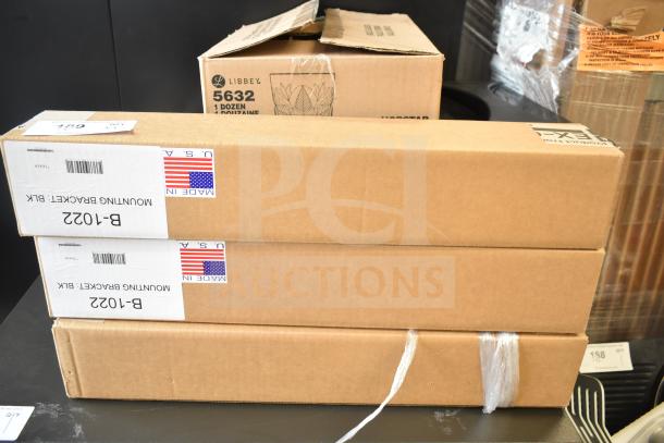 Three brand new Ex-Cell Kaiser B-1022 black steel mounting brackets in boxes. Each box labeled "MADE IN USA."