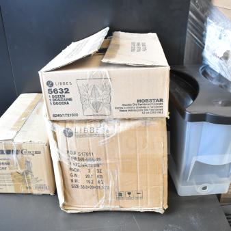 Four boxed items, including Choice CHEESECMB cheese slicer, Libbey 10 3/8" porcelain plates, Hobstar 12 oz. glasses, and Choice beverage dispenser.