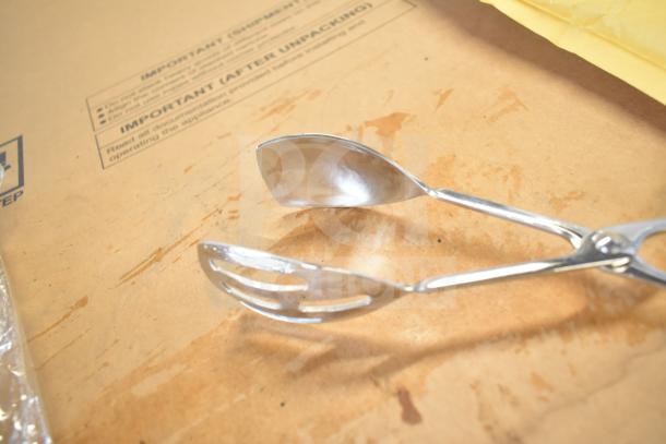 Metal tongs with one slotted end on a cardboard box marked “IMPORTANT.” Other items in lot not pictured.